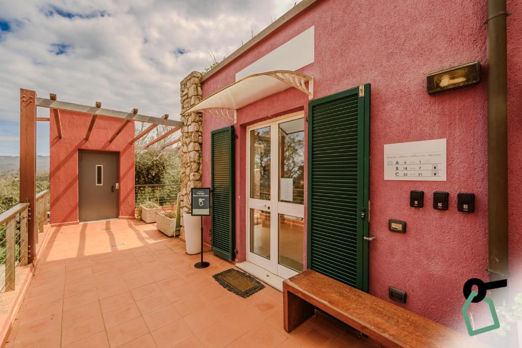 a pink building with green doors and a bench at Hotiday Apartments Portoferraio in Portoferraio