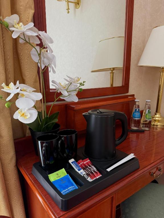 a tray with a coffee maker on a desk with flowers at Hotel Mazurkas in Ożarów Mazowiecki
