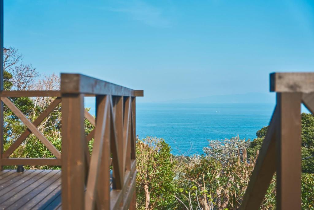 a wooden deck with the ocean in the background at プライベートリゾート熱川 in Higashiizu