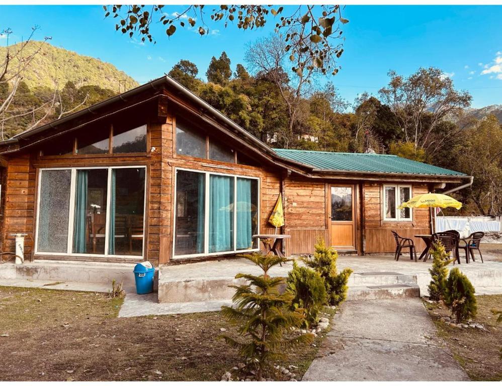 a log cabin with a table and an umbrella at Alaknanda Adventure Resort and Rafting Camp in Nandaprayāg