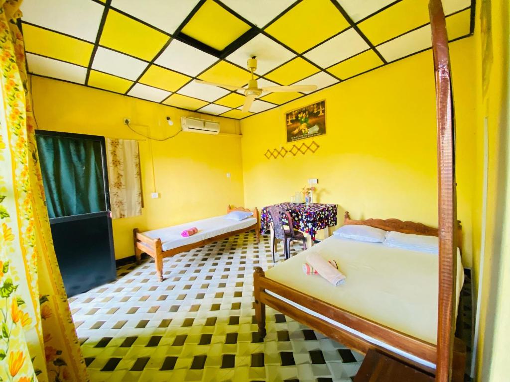 NikawatawanaChinna cottage的一间设有两张床和黄色墙壁的客房