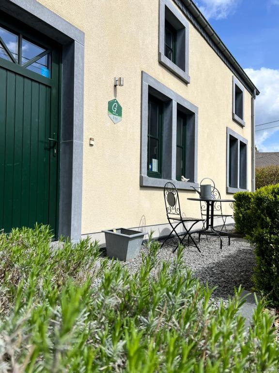 a house with a green door and a table and chairs at Gîte La Clef des Champs in Libin