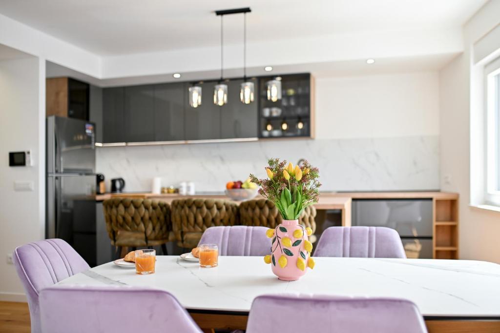 una cocina con una mesa con sillas moradas y un jarrón de flores en Lo-Lo Apartment, en Zadar