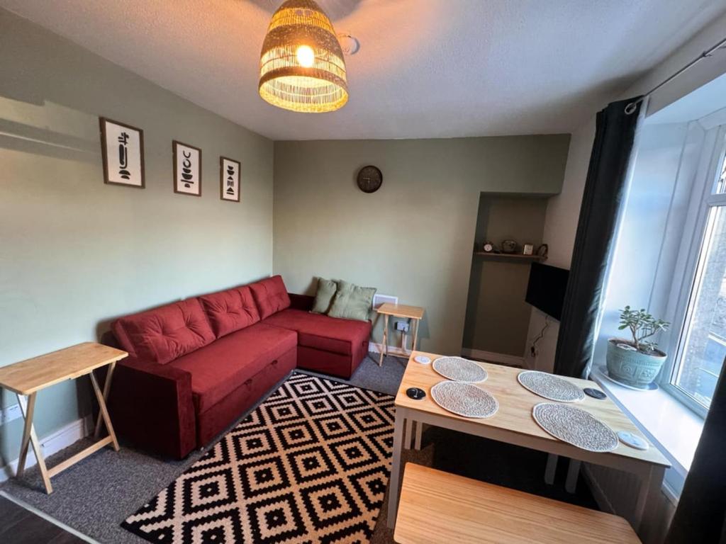 a living room with a red couch and a table at One Bedroom Apartment - Swansea Centre & Train stn in Swansea