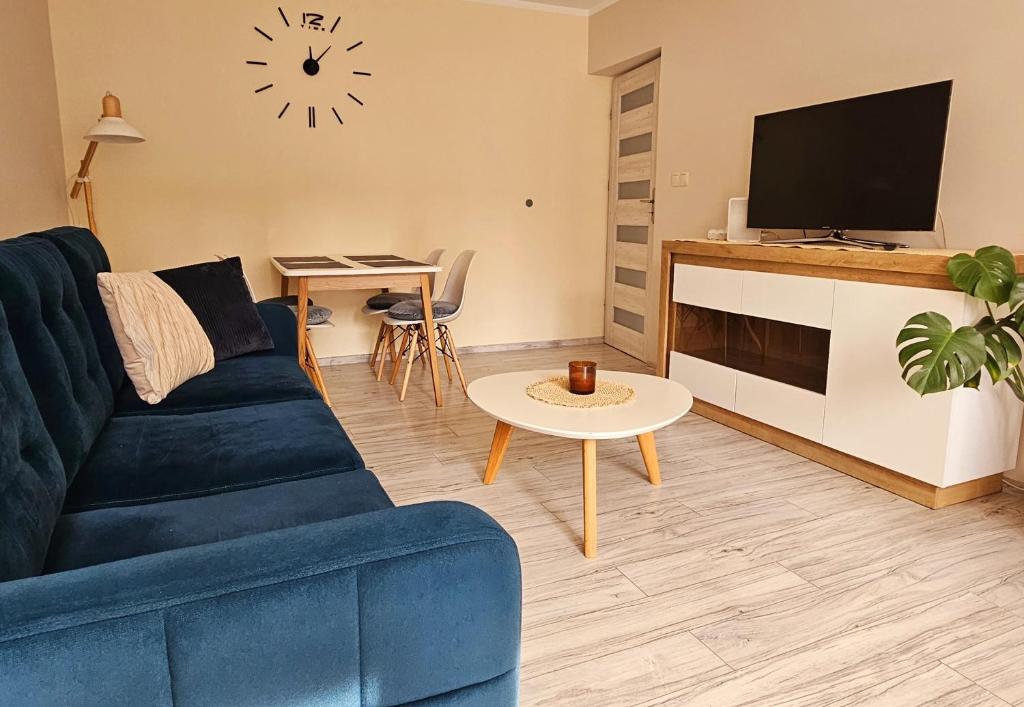 Una sala de estar con un sofá azul y un televisor. en Lubela, en Kołobrzeg