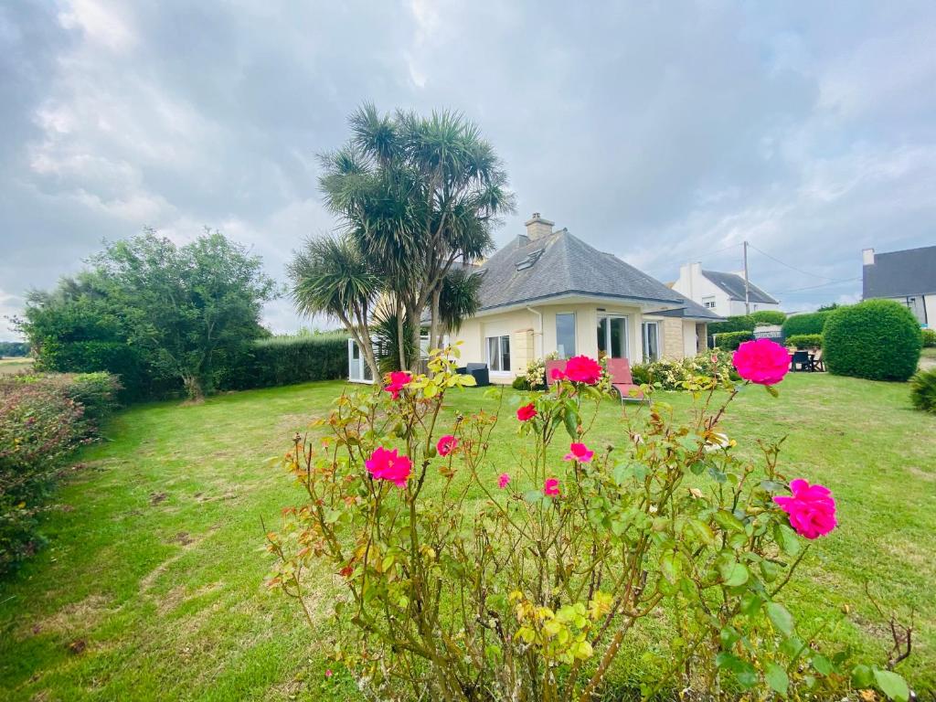 une maison avec des fleurs roses devant une cour dans l'établissement Ty Névez, à Sibiril