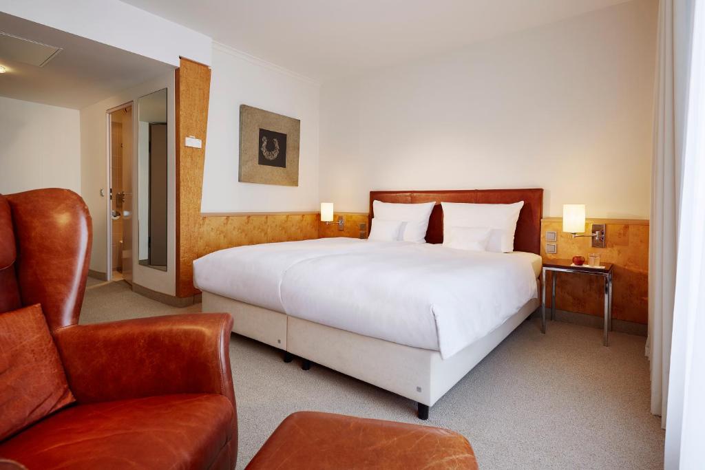 a hotel room with two beds and a chair at Lindner Hotel Düsseldorf Airport in Düsseldorf