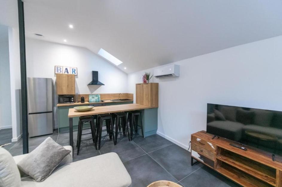 Il comprend un salon doté d'une cuisine avec une table et un canapé. dans l'établissement T3 spacieux avec terrasse et parking privatif, à Saint-Étienne