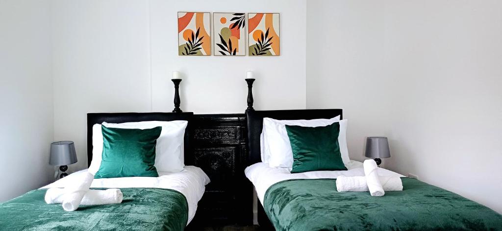 two beds with green and white pillows in a room at Spacious 4 Bedroom House-2 bathrooms-Contractor-Family-Relocation-Professionals-Parking-Close-to-All-Amenities in Luton