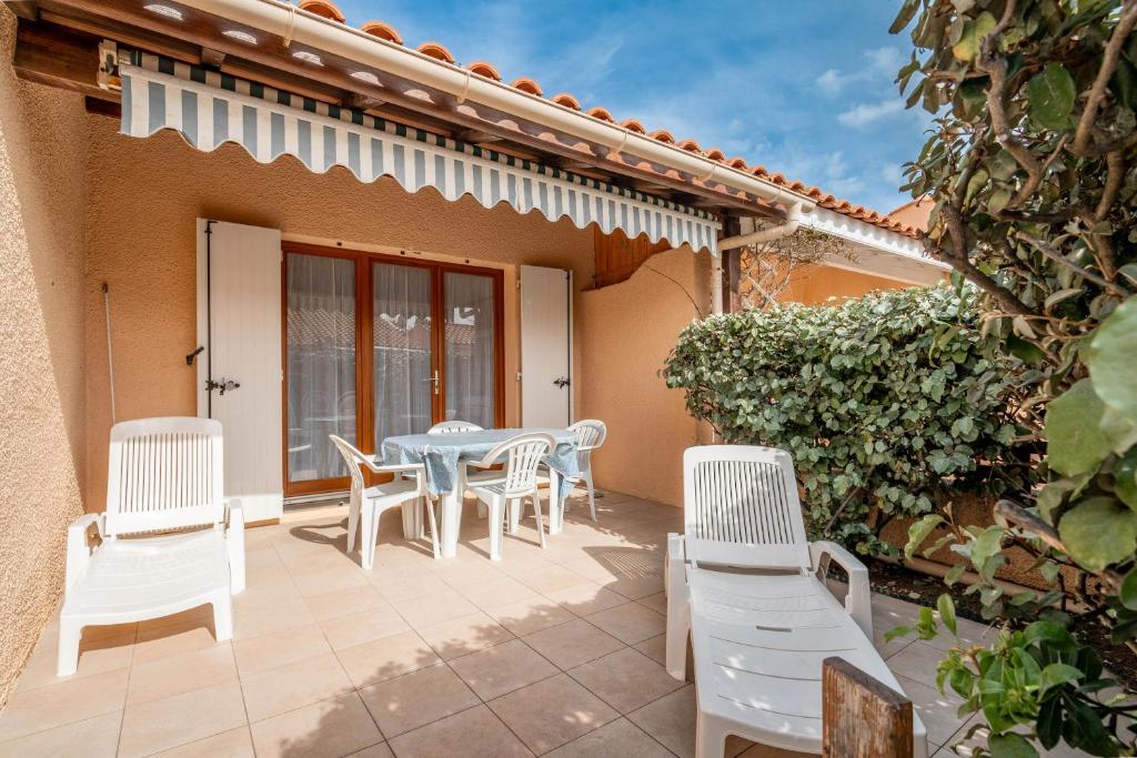eine Terrasse mit weißen Stühlen und einem Tisch in der Unterkunft Villa bord de mer in Gruissan