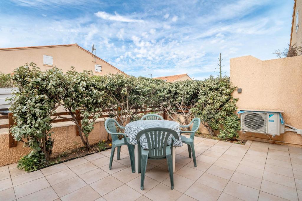 une table et des chaises sur une terrasse avec une haie dans l'établissement Villa bord de mer, à Gruissan