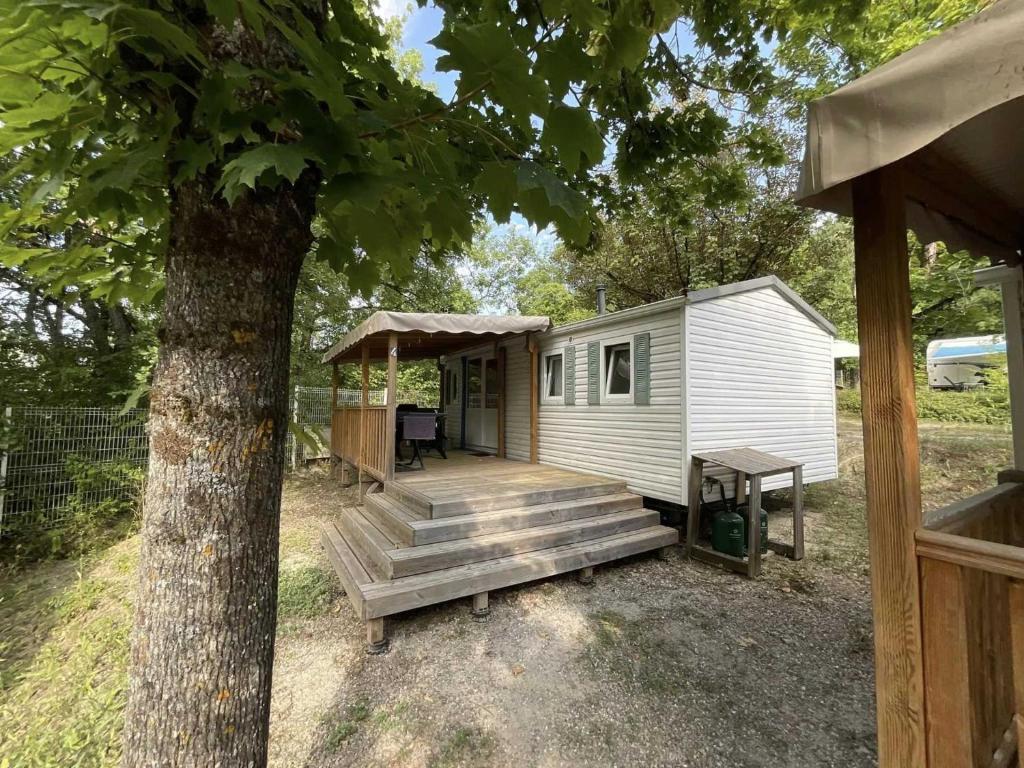 une petite maison avec une véranda et un arbre dans l'établissement Camping 3 étoiles - ccbb0fe, à Tallard