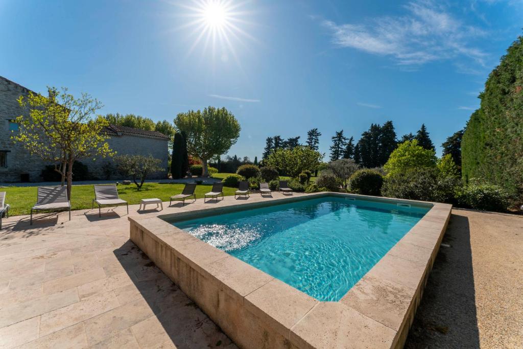 une piscine dans un jardin avec des chaises longues et du soleil dans l'établissement Mas De Charme Caumont Sur Durance, à Caumont-sur-Durance