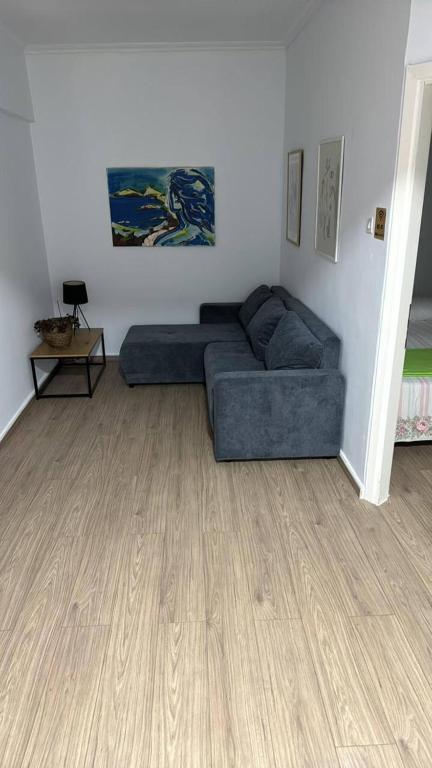 a living room with a blue couch and a wooden floor at BIRDS VIEW SERRES Διαμέρισμα στο Κέντρο in Serres