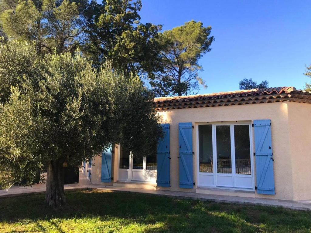 a house with blue doors and a tree at Villa "belles feuilles" avec piscine et tennis in Trans-en-Provence