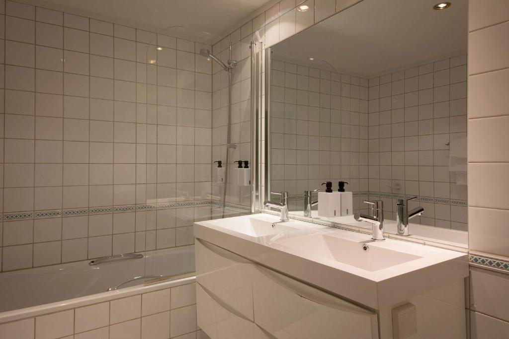 a bathroom with a sink and a tub and a mirror at Scandic Victoria in Oslo
