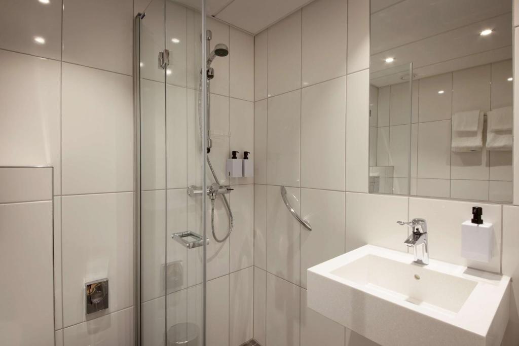 a white bathroom with a sink and a shower at Scandic Victoria in Oslo