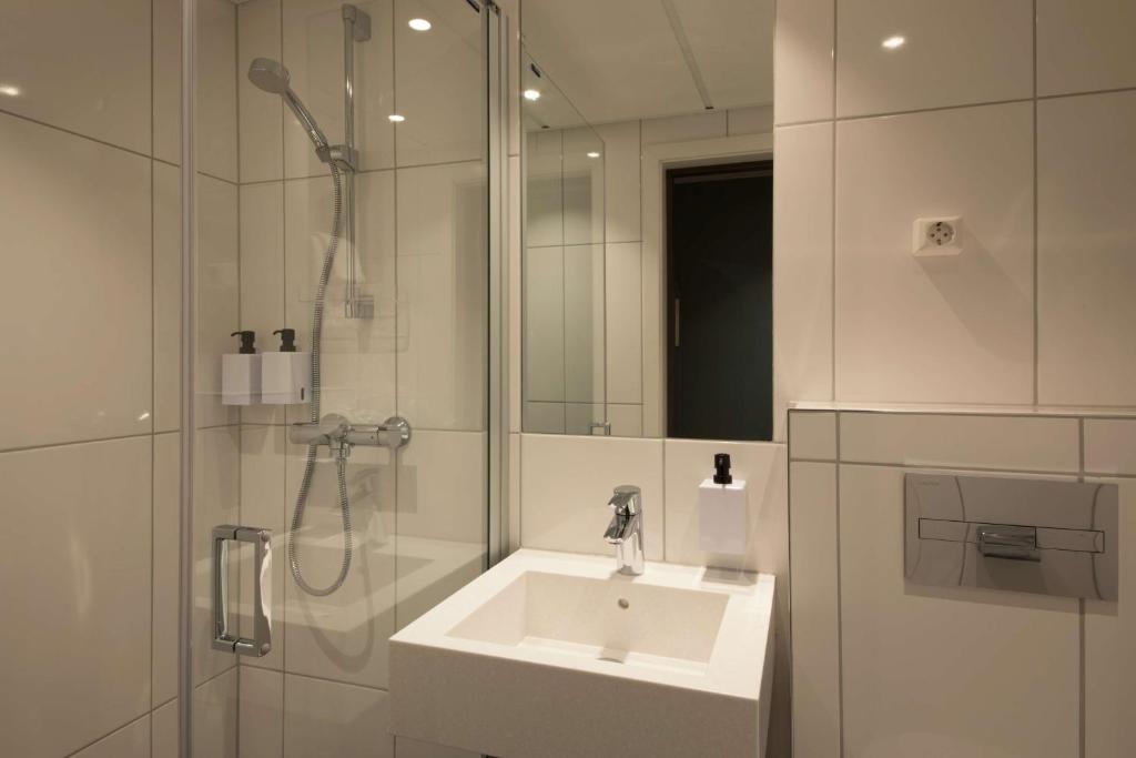 a white bathroom with a sink and a shower at Scandic Victoria in Oslo