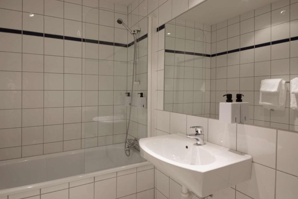 a white bathroom with a sink and a tub at Scandic Victoria in Oslo