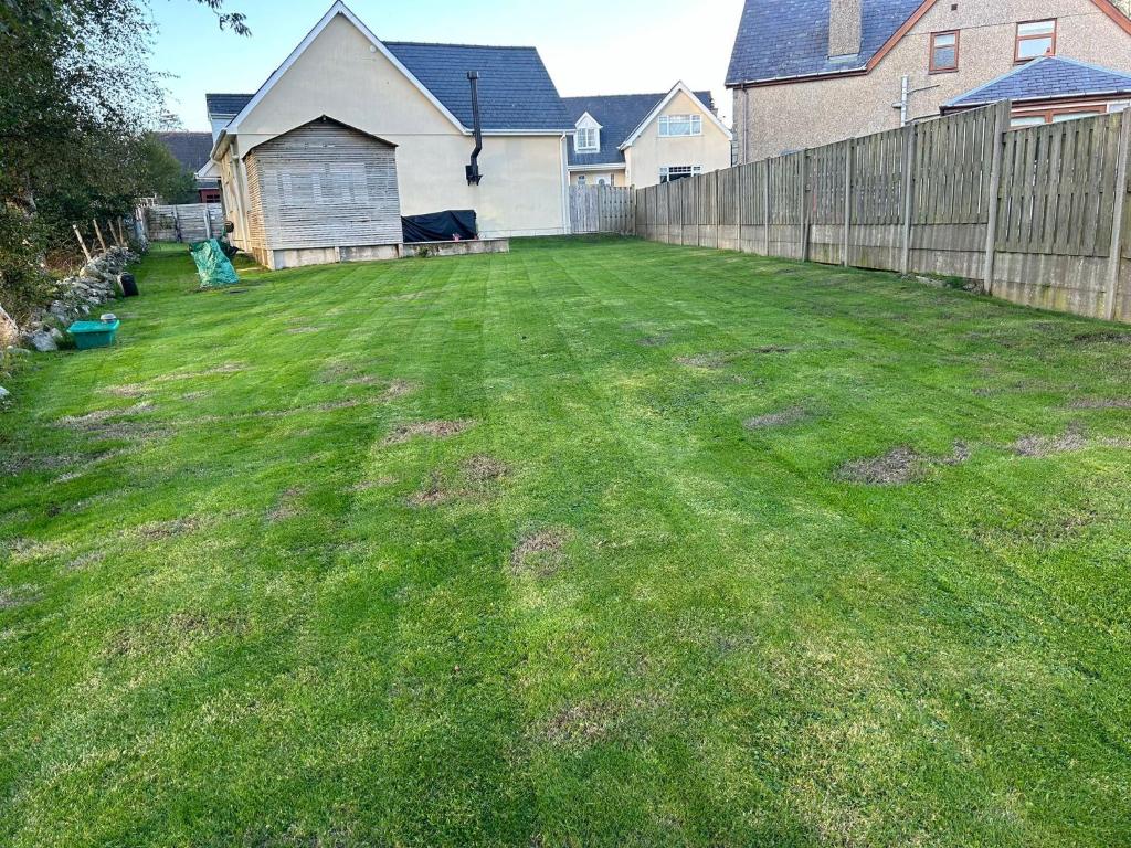 a yard with a fence and green grass at Cysgod Y Dyffryn - Luxury holiday cottage sleeping 8, Hot Tub available in Pen-y-groes