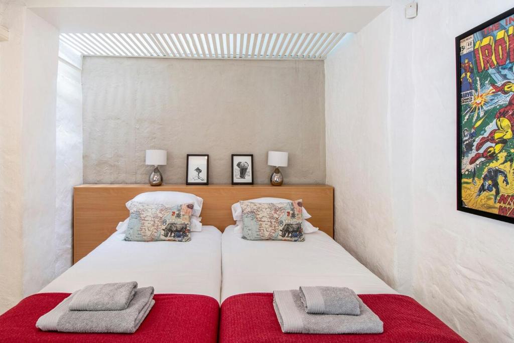 two beds in a bedroom with red sheets and pillows at See Table Mountain from a Historic Home in Cape Town