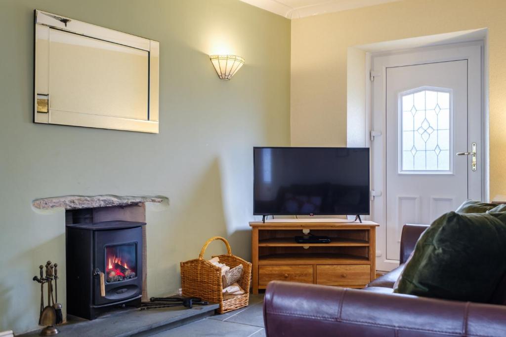 a living room with a fireplace and a television at Victory Cottage in Ambleside