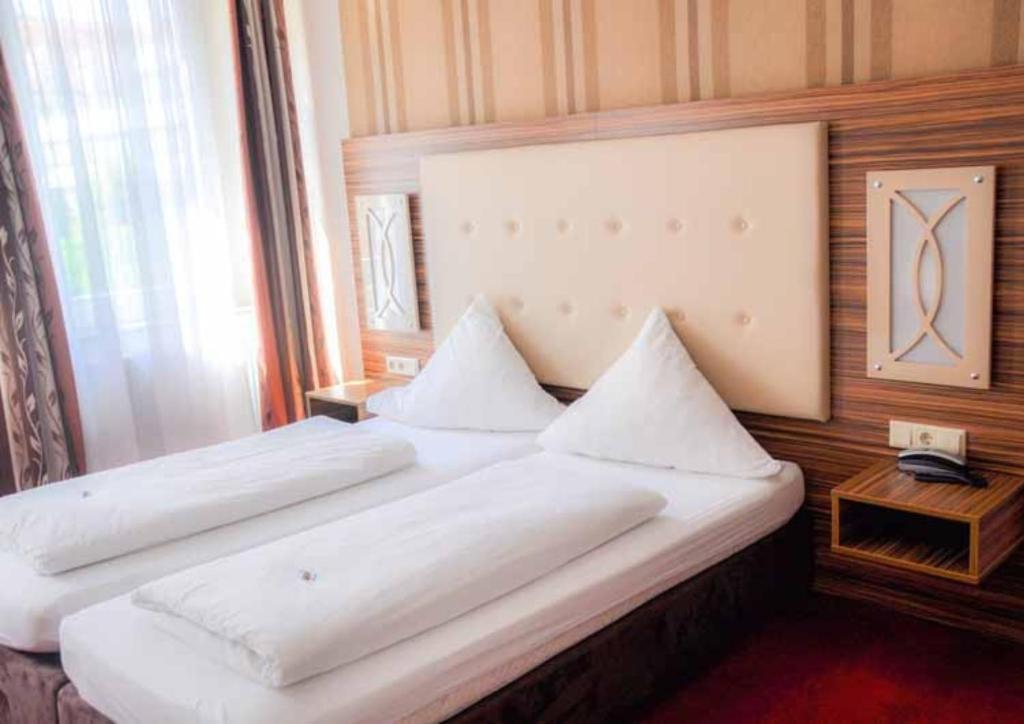 a large white bed in a room with a window at Hotel Villa Erlen in Erlangen