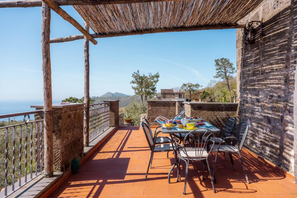 Un patio con una mesa y sillas en un balcón. en Casa Li Galli with sea view, en SantʼAgata sui Due Golfi