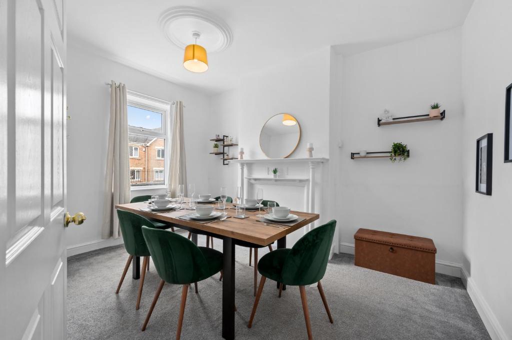 a dining room with a table and green chairs at Cosy 3-Bed House in Blackrod in Blackrod