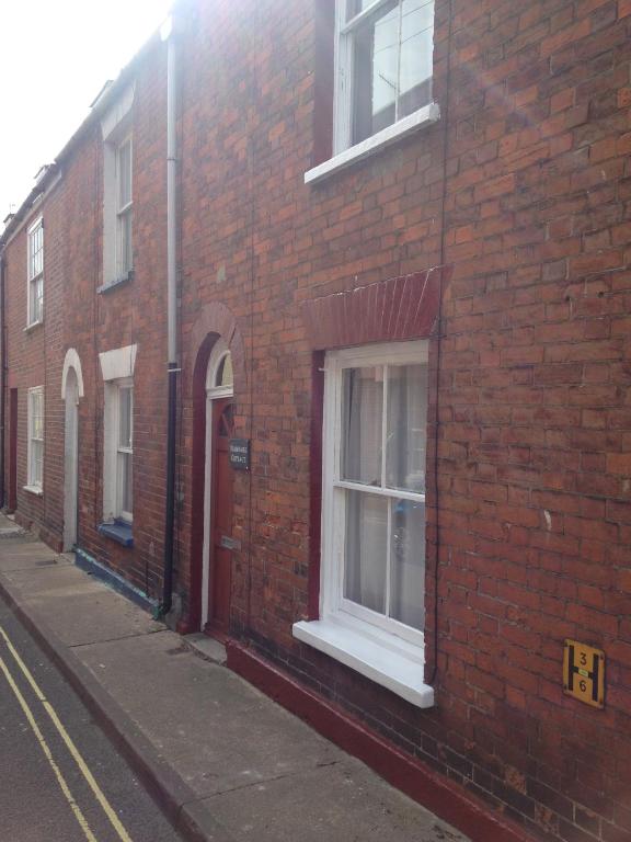 a red brick building with a window on a street at Isambard Cottage in Weymouth