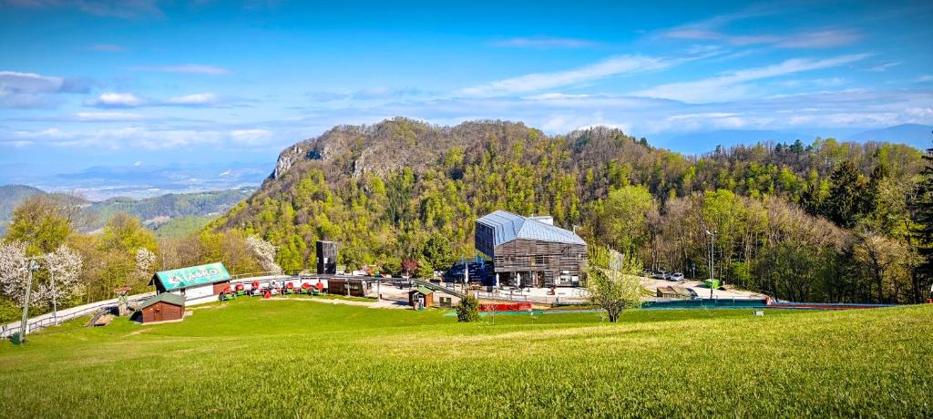 un edificio su un campo erboso di fronte a una montagna di Hotel Celjska Koca a Celje