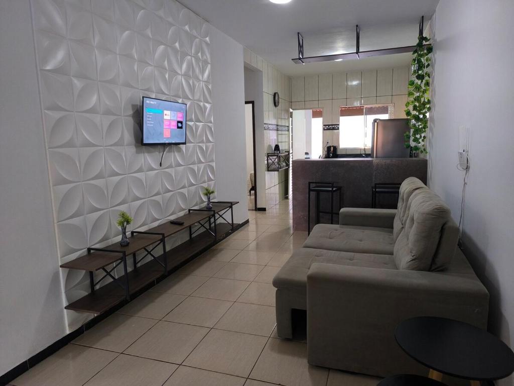 a living room with a couch and a tv on a wall at Casa Grande com área Gourmet e Garagem in Montes Claros