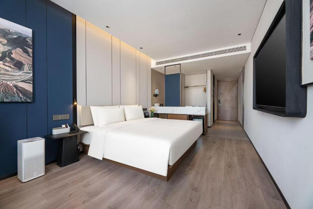 una camera con un grande letto bianco e una TV di Atour Hotel Qingdao Taidong Beer Street a Qingdao