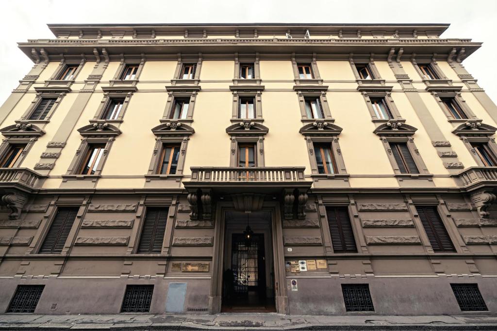 フィレンツェにあるホテル ドゥーカ ダオスタのバルコニー付きの大きな黄色の建物
