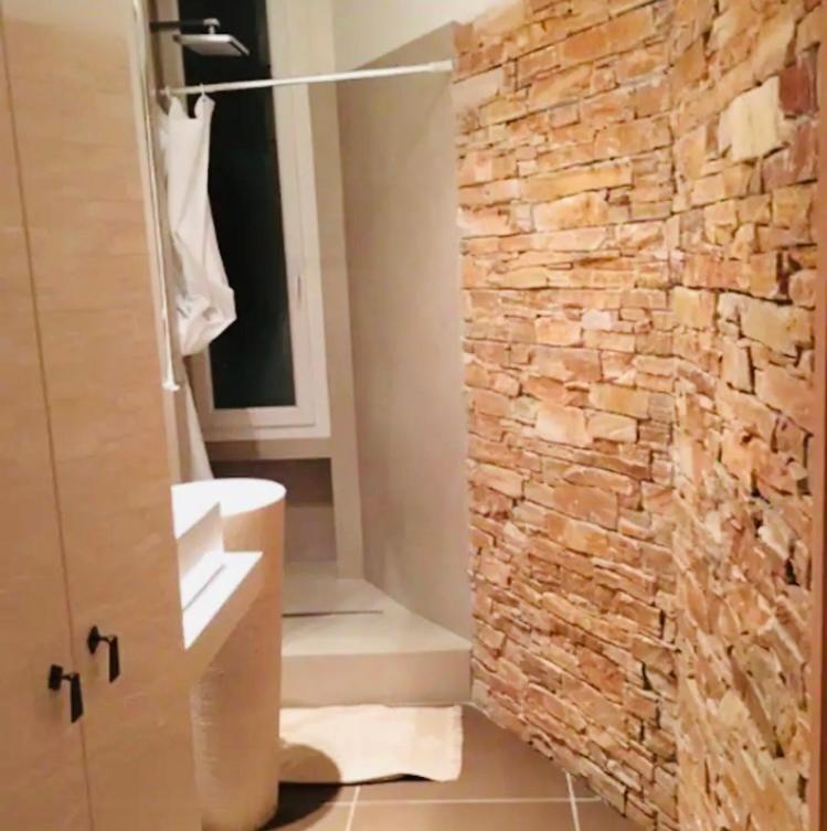 La salle de bains est pourvue d'un mur en pierre et d'une douche. dans l'établissement T2 pied dans l eau, à Ajaccio