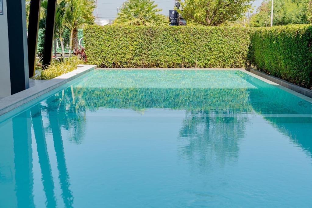 a swimming pool with blue water in front of a hedge at The City Hatyai D20 in Sathani Khlong Rian