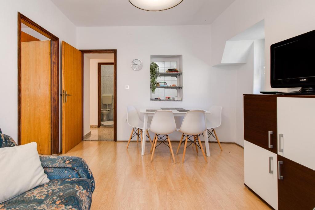 Una sala de estar con una mesa y sillas y un televisor. en Apartments Kurdija, en Punat