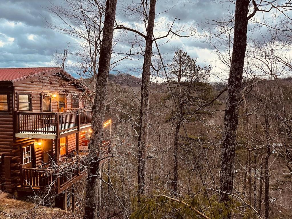 a log cabin in the woods with lights on at Cozy Secluded Cabin Firepit Hot Tub in Pigeon Forge