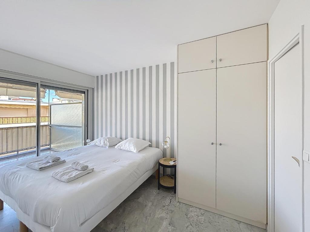 une chambre avec un lit blanc et une grande fenêtre dans l'établissement Appartement Canto bright appartement Croisette beach, à Cannes