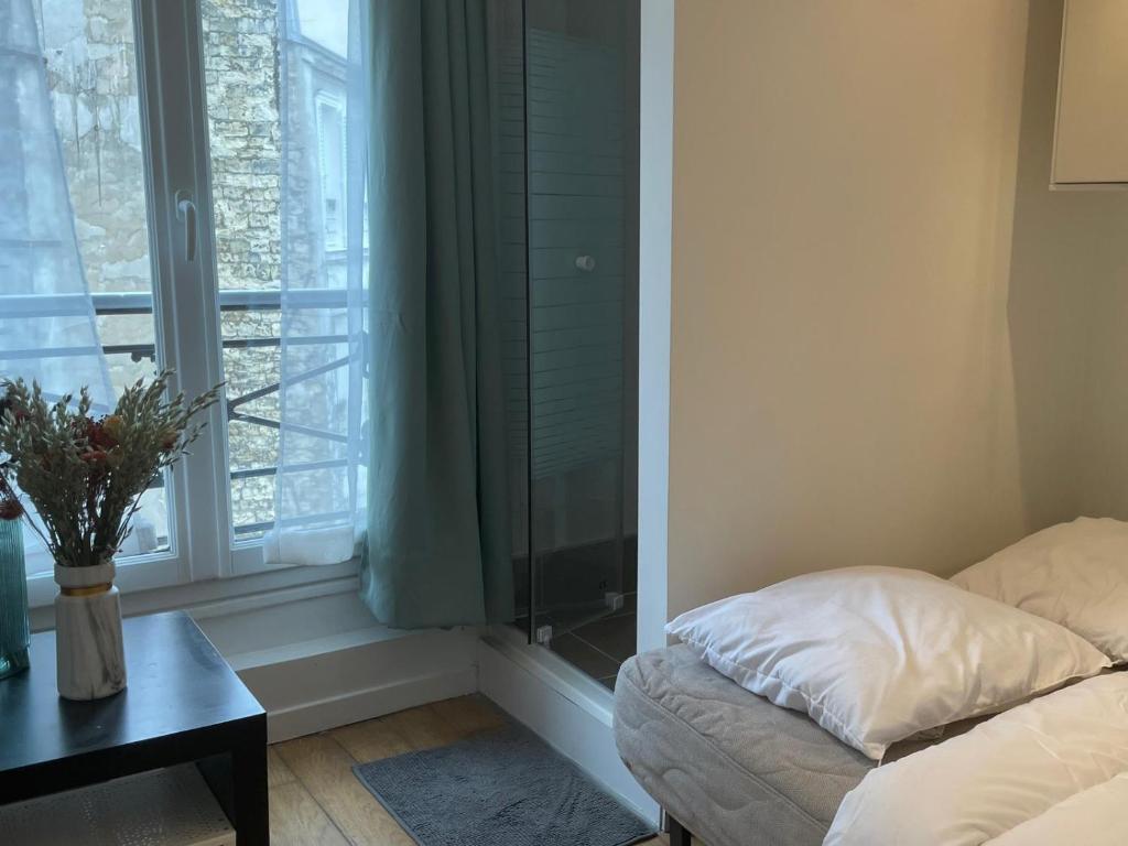 Cette chambre dispose d'une fenêtre avec un lit et une table. dans l'établissement Au petit Cuvier Paris 5, à Paris