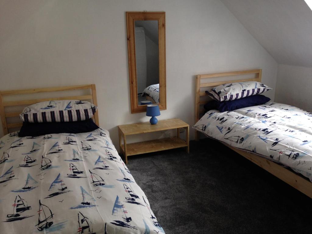 een slaapkamer met twee bedden en een spiegel bij Isambard Cottage in Weymouth