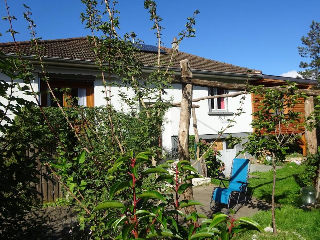 une maison avec une chaise bleue dans le jardin dans l'établissement family home, à Baume-les-Dames