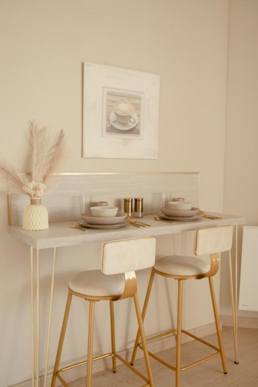 une table à manger avec deux chaises et une table avec des assiettes dans l'établissement Studio meublé Le Refuge doré avec Netflix, à Homécourt