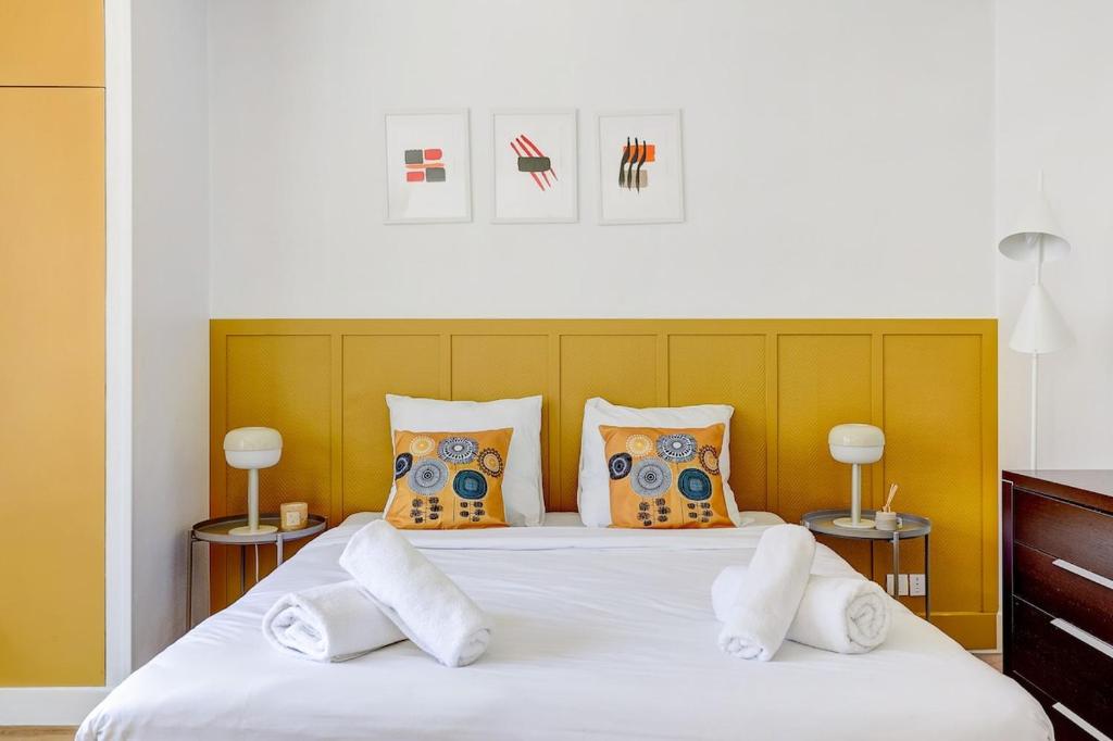 une chambre avec un grand lit blanc avec des oreillers dans l'établissement Eiffel residence Augustin, à Paris