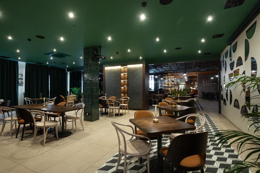 restauracja ze stołami i krzesłami oraz zielonym sufitem w obiekcie Gold Hotel w mieście Złotoryja