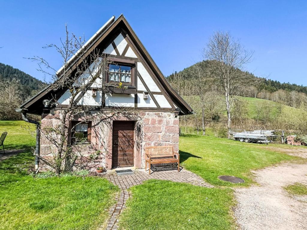 ein kleines Steinhaus mit einer Bank auf einem Feld in der Unterkunft Holiday Home Backhäusle by Interhome in Unterehlenbogen