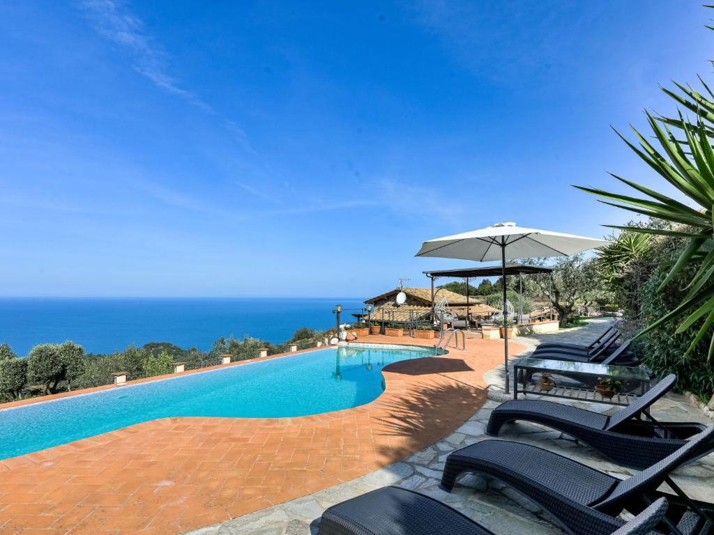 Una piscina con sillas y sombrilla y el océano. en Villa Ricali by Interhome, en Porto Santo Stefano
