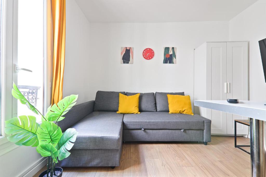 un salon avec un canapé gris et des coussins jaunes dans l'établissement Studio Appartement Quartier Tour Eiffel 10 Free Netflix, à Paris