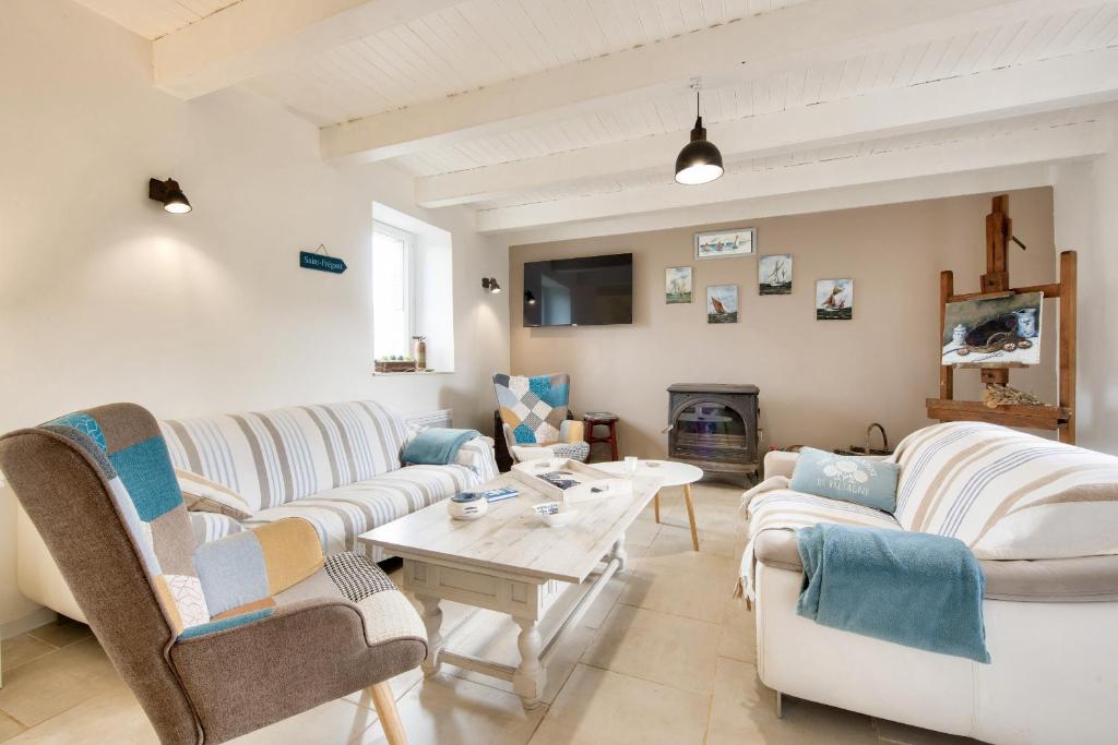 Maison pour 6 avec jardin, terrasse et jeux في Saint-Frégant: غرفة معيشة مع أريكتين وطاولة