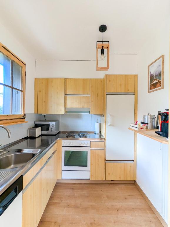 a kitchen with wooden cabinets and a white refrigerator at Rare, quite & centered Apartment with Garden & Fireplace in Villars-sur-Ollon